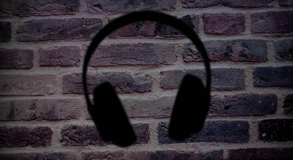 a silhouette of overear headphones set against a brick wall