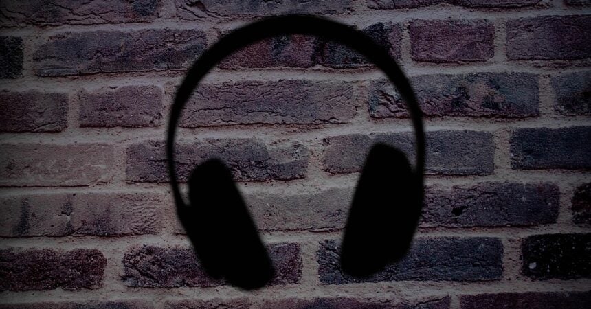 a silhouette of overear headphones set against a brick wall