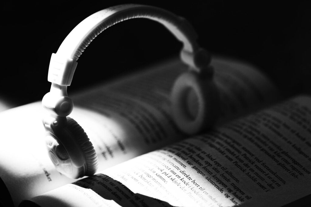 white overear headphones balanced on top of the pages of an open book