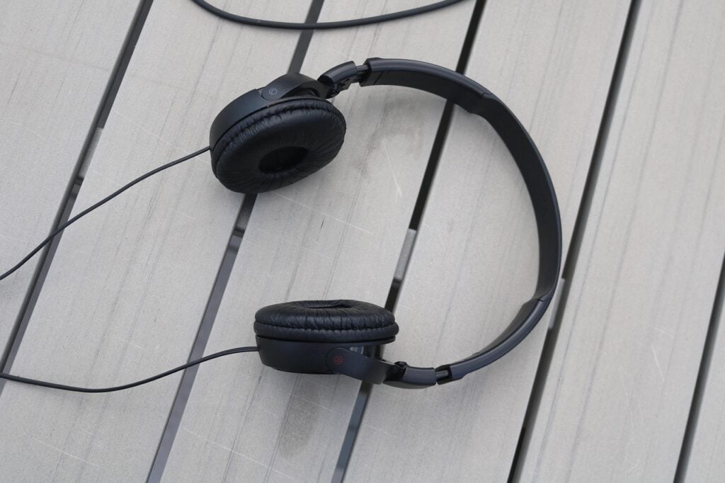 black wired headphones lying on a slatted wood surface