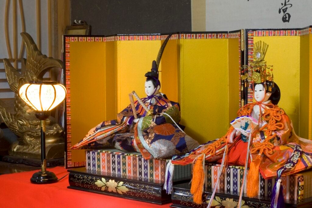emperor and empress dolls atop a hina doll stand
