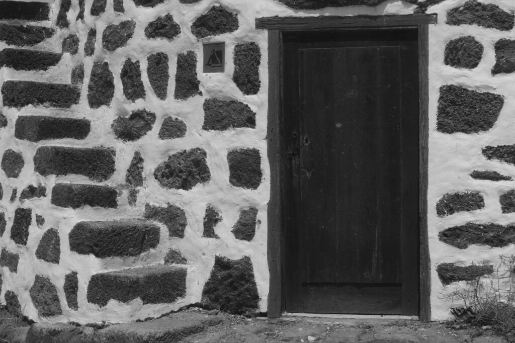 a dark wood door set in a wall made of stone with wide white grout between each stone