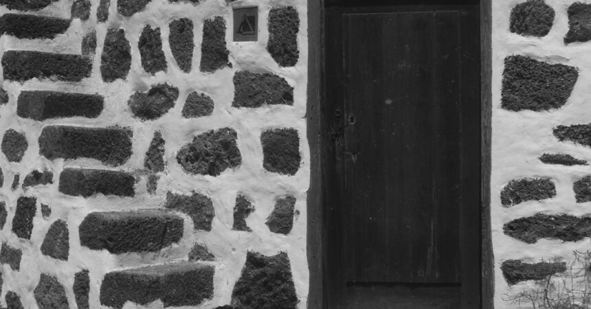 a dark wood door set in a wall made of stone with wide white grout between each stone