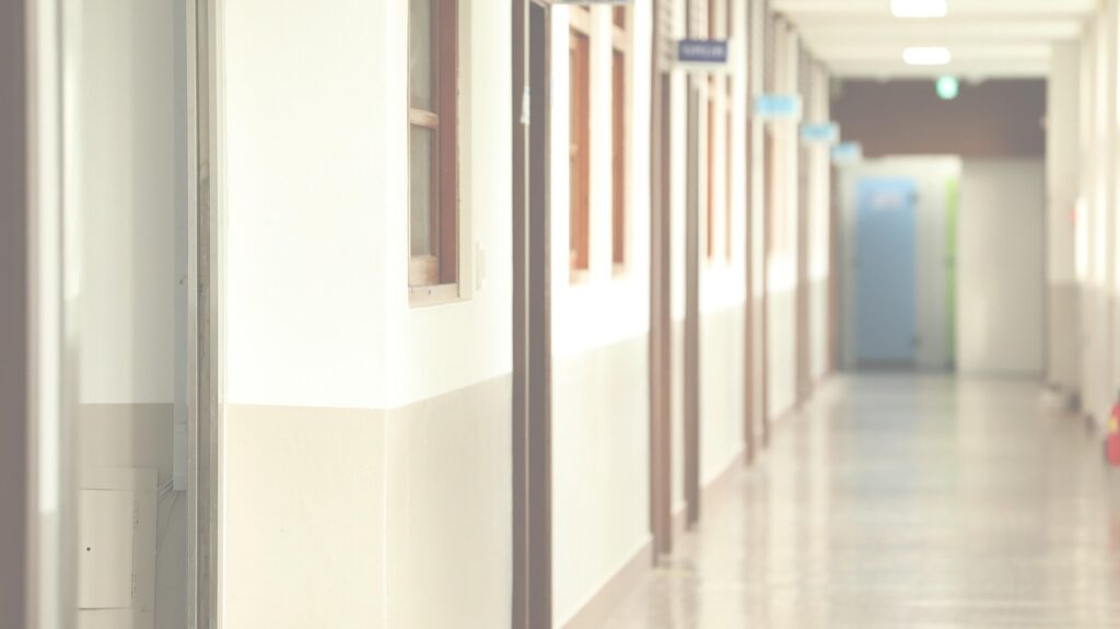 a brightly lit hallway in a korean high school with doors all down the lefthand side