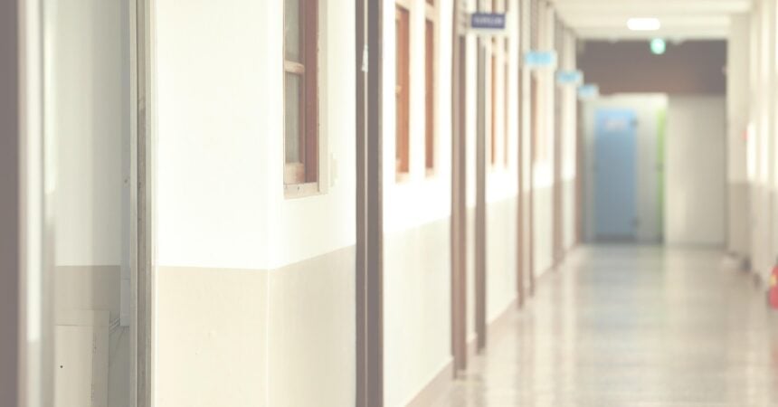 a brightly lit hallway in a korean high school with doors all down the lefthand side