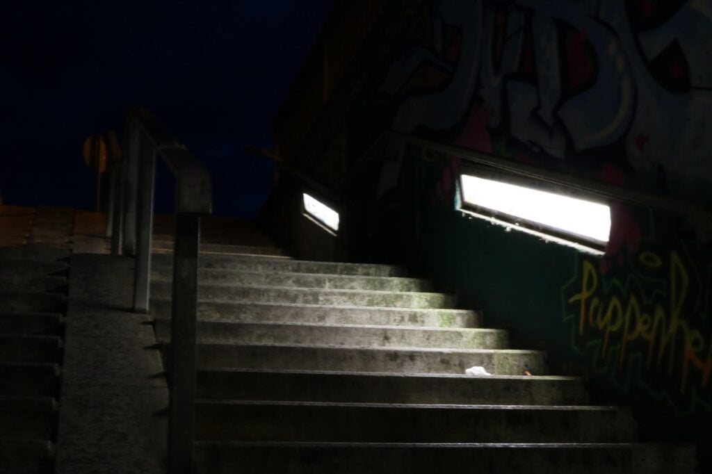 looking up a set of cemet stairs in the dark. it is lit by lamps on the sides
